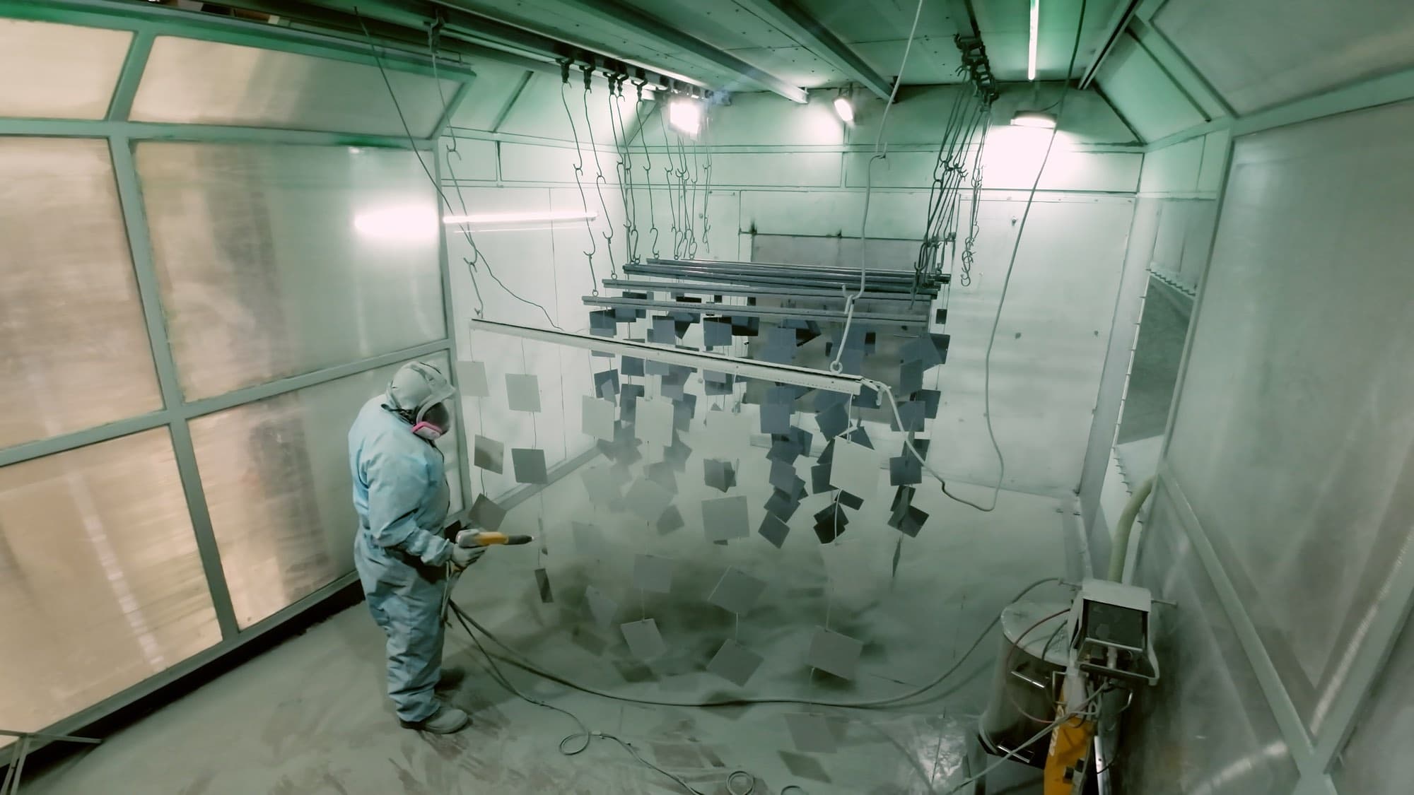 Cabina de pintura electrostática con piezas colgadas durante la aplicación del recubrimiento en Formet CNC, Monterrey